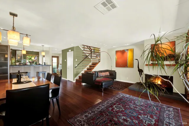a living room with furniture and a dining table with wooden floor