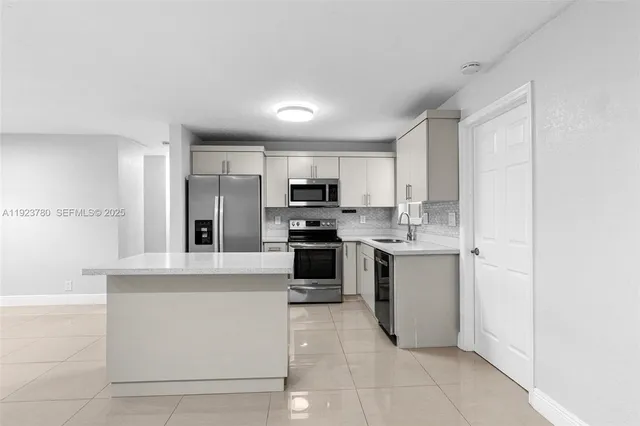 a kitchen with stainless steel appliances granite countertop a refrigerator and a stove top oven