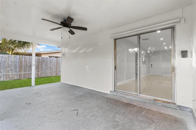 an empty room with floor to ceiling fan and windows
