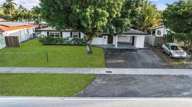 a view of a white house next to a yard with big trees