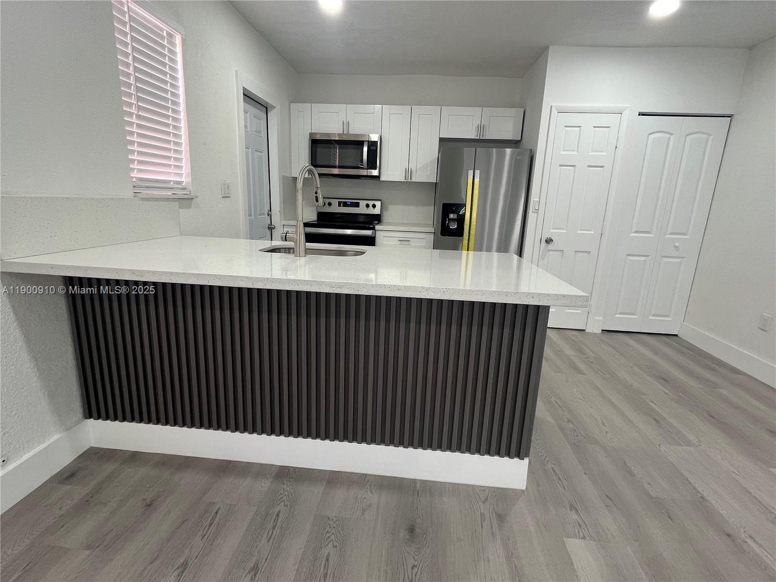 1923 Northwest 66th Street Miami, FL 33147 - Photo 13 of 27 a kitchen with a sink a refrigerator and window