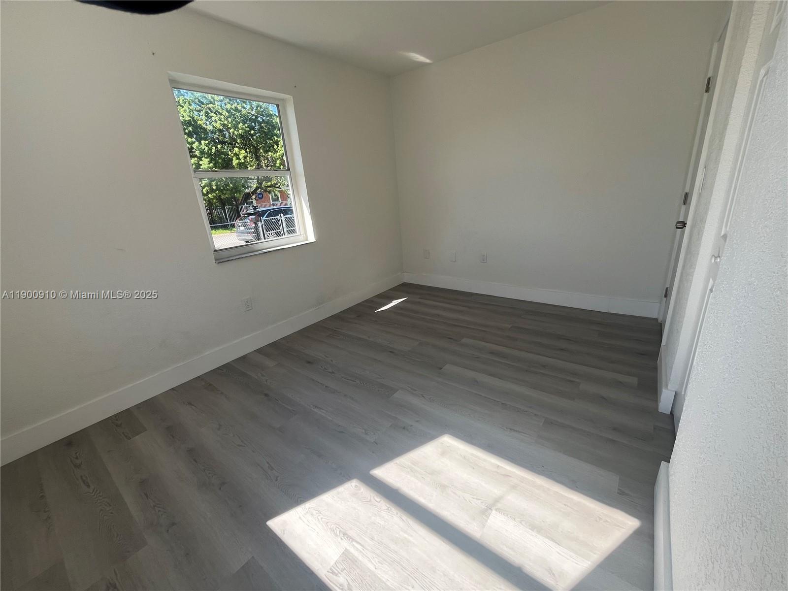 1923 Northwest 66th Street Miami, FL 33147 - Photo 18 of 27 an empty room with wooden floor and windows