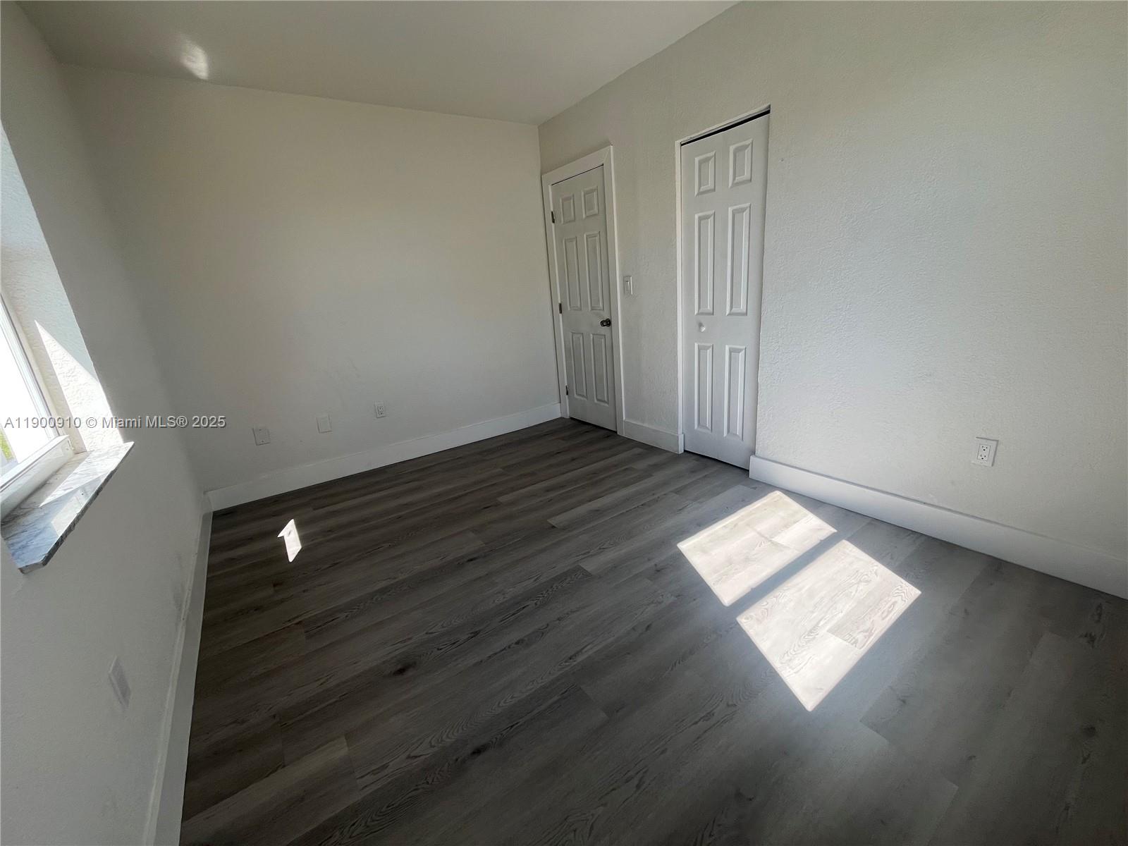 1923 Northwest 66th Street Miami, FL 33147 - Photo 19 of 27 an empty room with wooden floor and windows