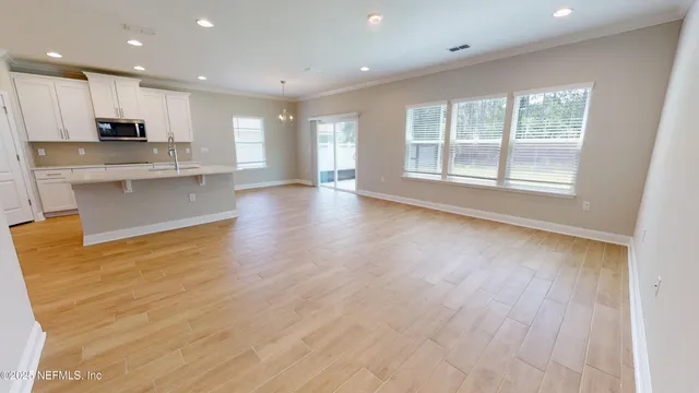 a view of kitchen with kitchen island wooden floors wooden cabinets and appliances