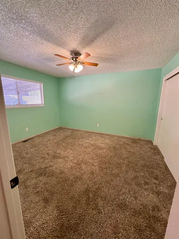 a view of an empty room with window and chandelier fan