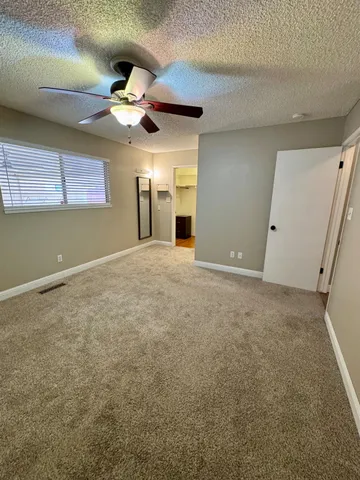an empty room with a chandelier fan and windows
