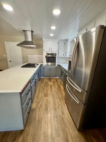 a kitchen with stainless steel appliances a refrigerator a stove a sink and a oven