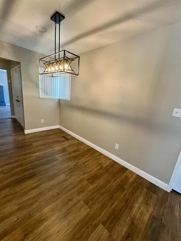 a view of a room with wooden floor chandelier and a ceiling fan