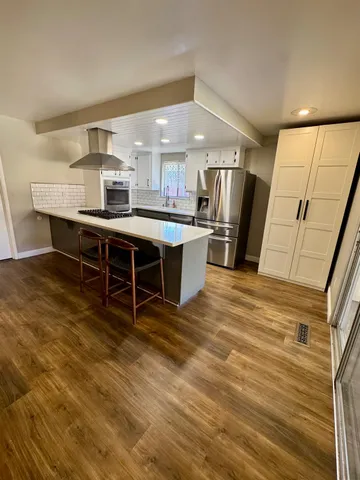a kitchen with stainless steel appliances a sink cabinets and wooden floor