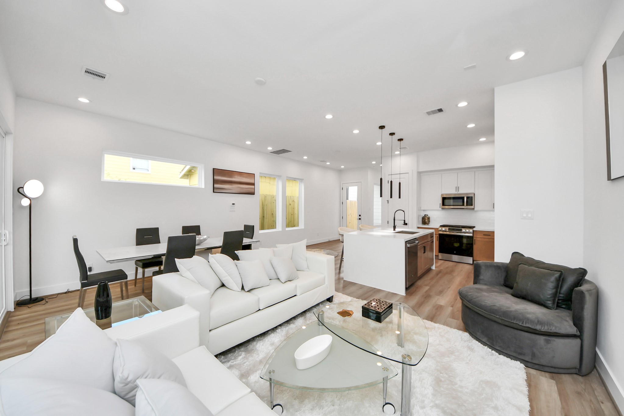 505 Middle Street Houston, TX 77003 - Photo 14 of 46 This modern, open-concept living room seamlessly blends into a sleek kitchen, featuring elegant white walls, warm wood floors, and abundant natural light, creating a bright and inviting space perfect for relaxation and entertaining.