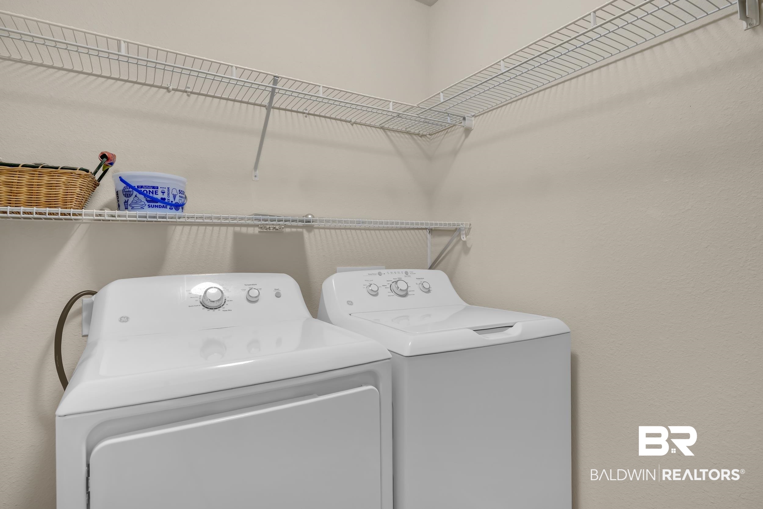 1704 Abbey Loop Foley, AL 36535 - Photo 29 of 38 Dedicated laundry space featuring a white top-load washer and dryer set, neutral wall tones, and overhead wire shelving for organization