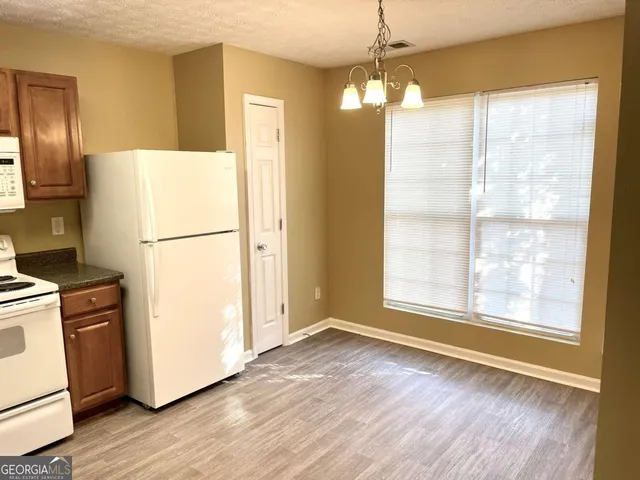 a view of a kitchen with wooden floor and a refrigerator