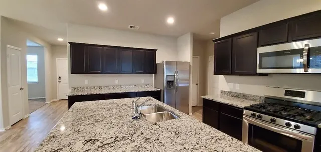 a kitchen with stainless steel appliances granite countertop a stove a sink and a microwave