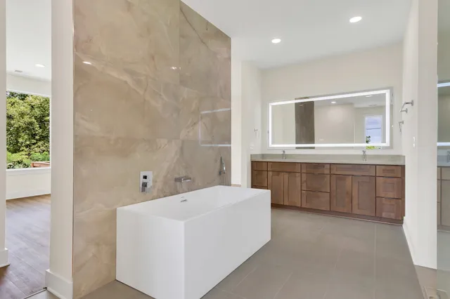 a bathroom with a double vanity sink a mirror and a bathtub