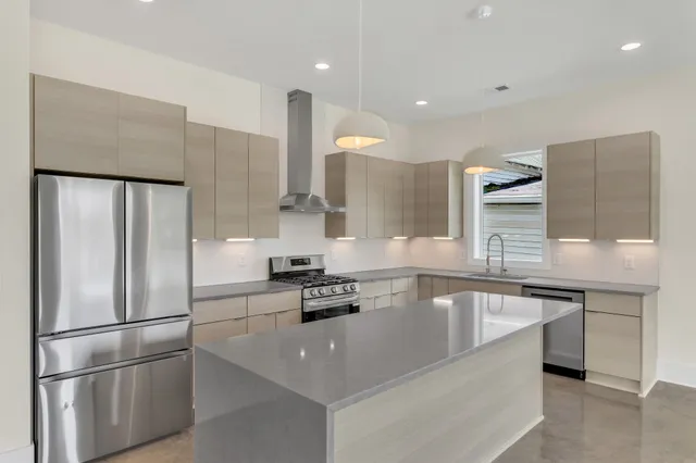 a kitchen with stainless steel appliances granite countertop a sink a stove and a refrigerator