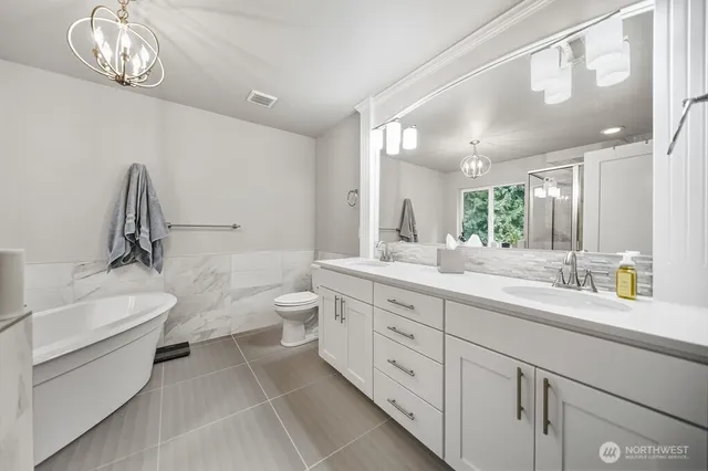 a spacious bathroom with a double vanity sink a toilet and a bathtub