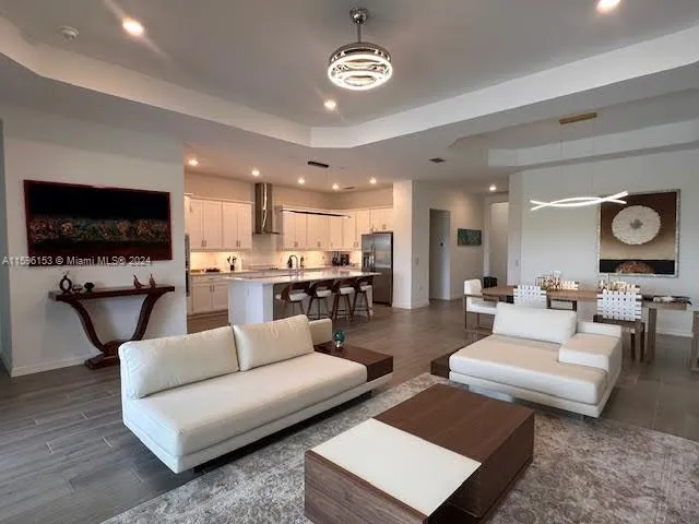 a living room with couches and kitchen view with wooden floor