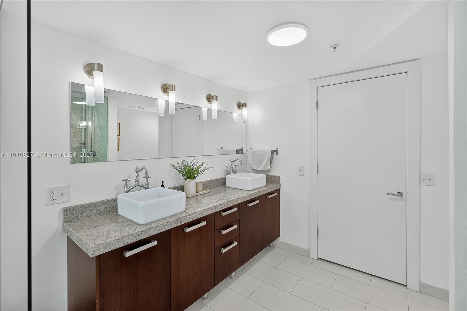 720 Northeast 62nd Street, Unit 311 Miami, FL 33138 - Photo 18 of 39 a bathroom with a granite countertop sink and a mirror