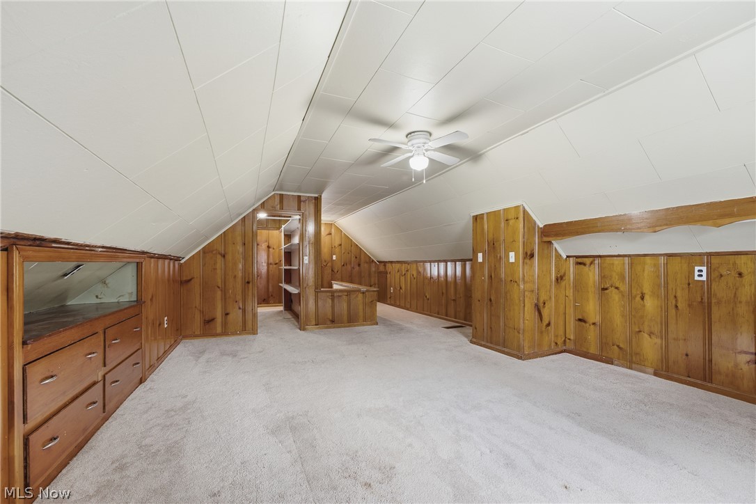 311 Fowles Road Berea, OH 44017 - Photo 25 of 40 Spacious carpeted room featuring sloped ceilings, wood paneling, a ceiling fan with light fixture, built-in cabinetry with drawers, and an open storage nook