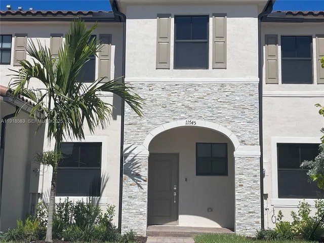 a front view of a house with garage and plants