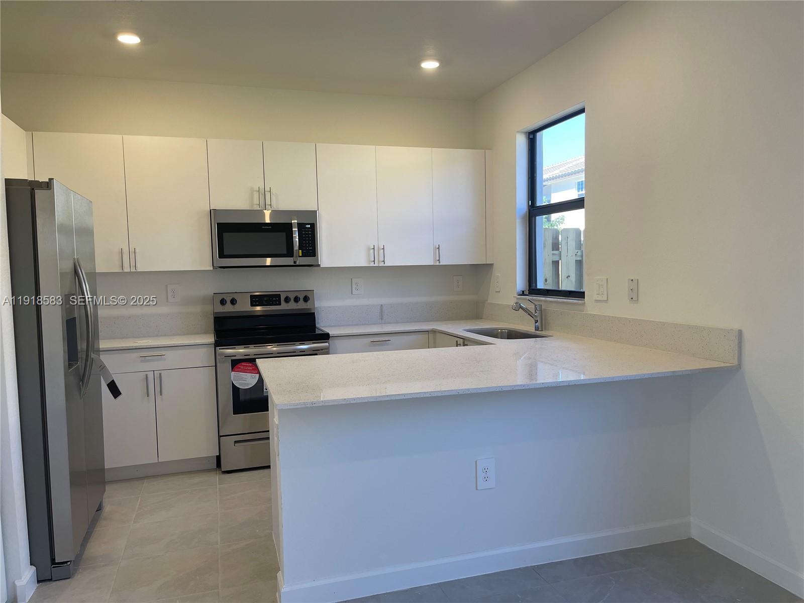 11745 Southwest 245 Terrace Homestead, FL 33032 - Photo 5 of 15 a kitchen with stainless steel appliances a sink stove refrigerator and a window