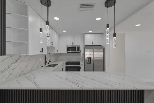 a kitchen with stainless steel appliances kitchen island granite countertop a refrigerator a sink and a stove