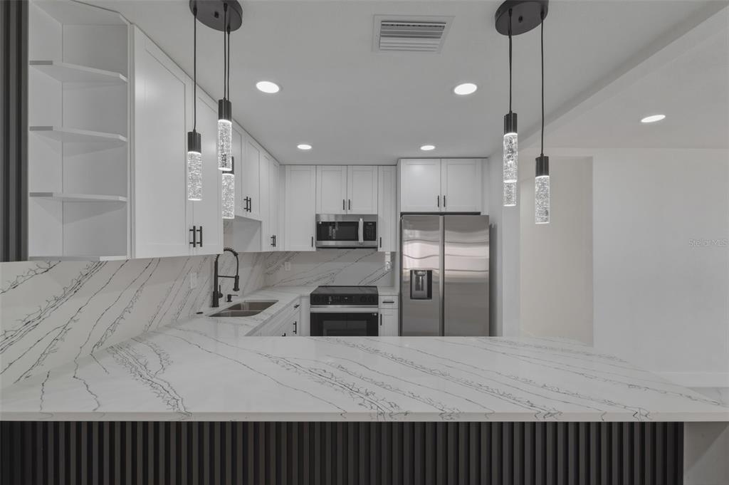 1413 May Street Lutz, FL 33548 - Photo 11 of 43 a kitchen with stainless steel appliances kitchen island granite countertop a refrigerator a sink and a stove