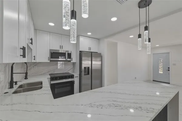 a kitchen with stainless steel appliances granite countertop a sink a stove and a refrigerator