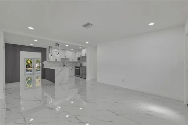 a view of kitchen with kitchen island a sink white cabinets and stainless steel appliances