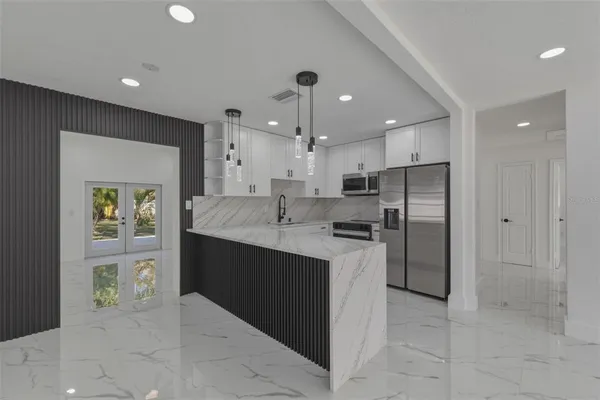 a kitchen with stainless steel appliances kitchen island granite countertop a refrigerator and a sink