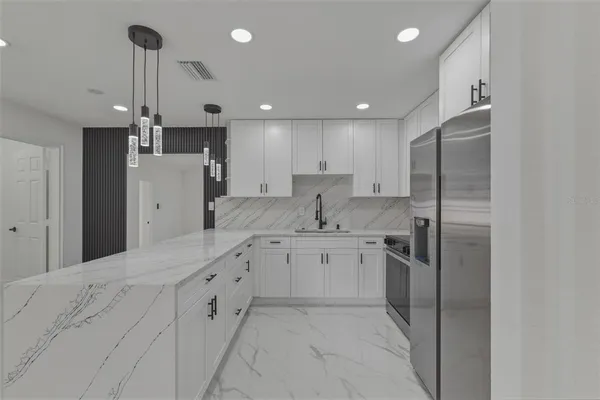 a kitchen with stainless steel appliances kitchen island granite countertop a refrigerator and a sink