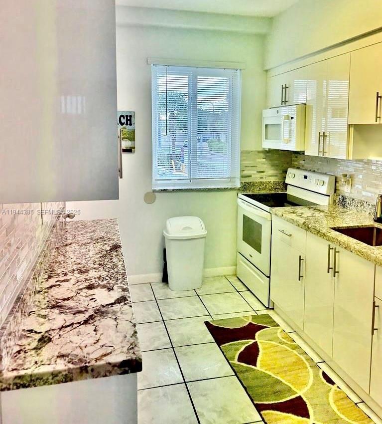326 Harrison Street, Unit 106A Hollywood, FL 33019 - Photo 14 of 22 a bathroom with a granite countertop sink and a stove