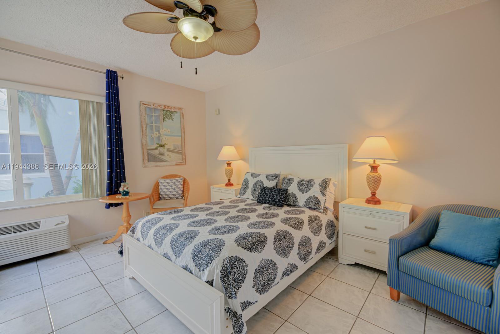 326 Harrison Street, Unit 106A Hollywood, FL 33019 - Photo 9 of 22 a bedroom with a bed and a chandelier
