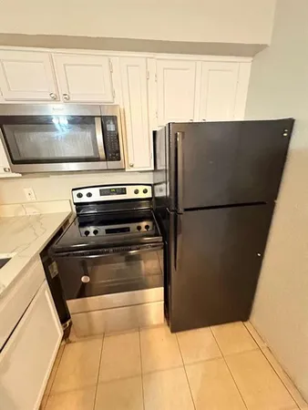 a kitchen with a refrigerator a stove top oven and cabinets