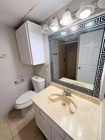 a bathroom with a granite countertop sink a toilet and a mirror