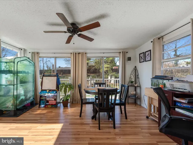 a dining room with wooden floor a chandelier fan a wooden table and chairs