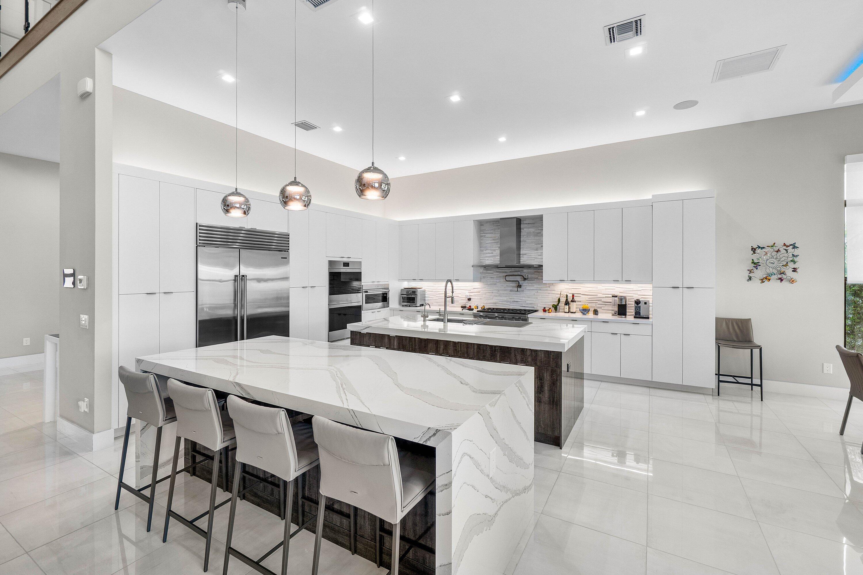 9657 Vescovato Way Boca Raton, FL 33496 - Photo 16 of 68 a kitchen with stainless steel appliances kitchen island granite countertop a table chairs sink and cabinets