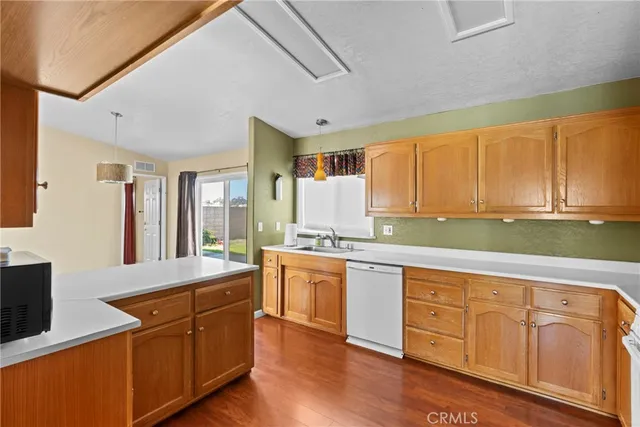 a large kitchen with kitchen island granite countertop a stove a sink dishwasher and white cabinets with wooden floor