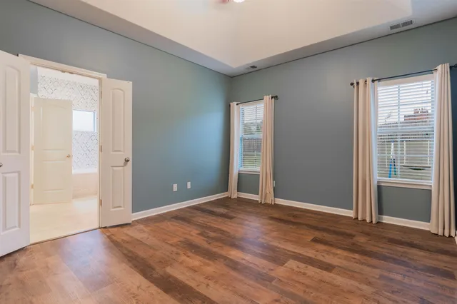 a view of an empty room with wooden floor and windows