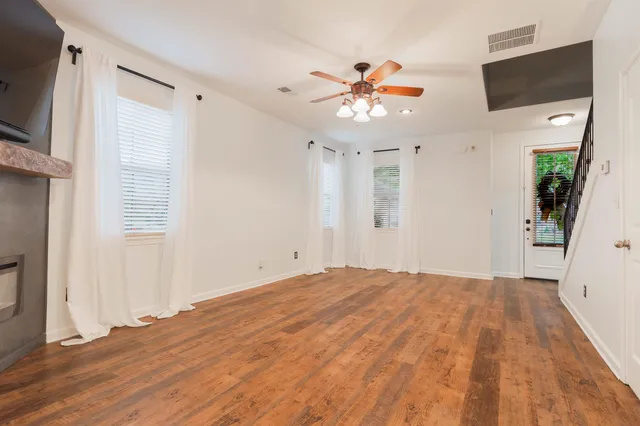 a view of an empty room with wooden floor and a flat screen tv