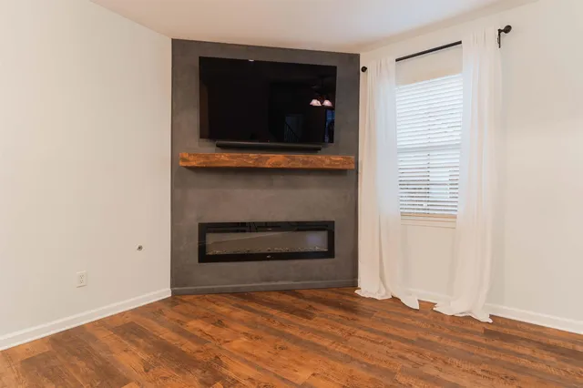a view of empty room with wooden floor and fireplace