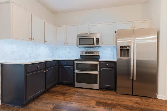 a kitchen with granite countertop a refrigerator and microwave