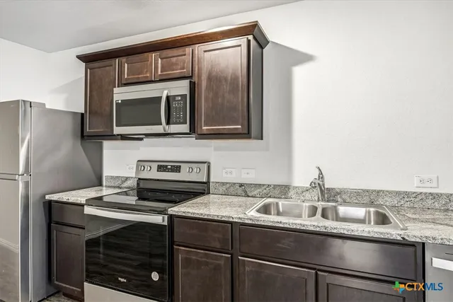 a view of a kitchen with a sink and a refrigerator