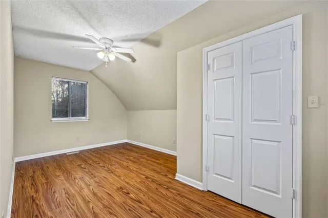 an empty room with a chandelier fan and wooden floor
