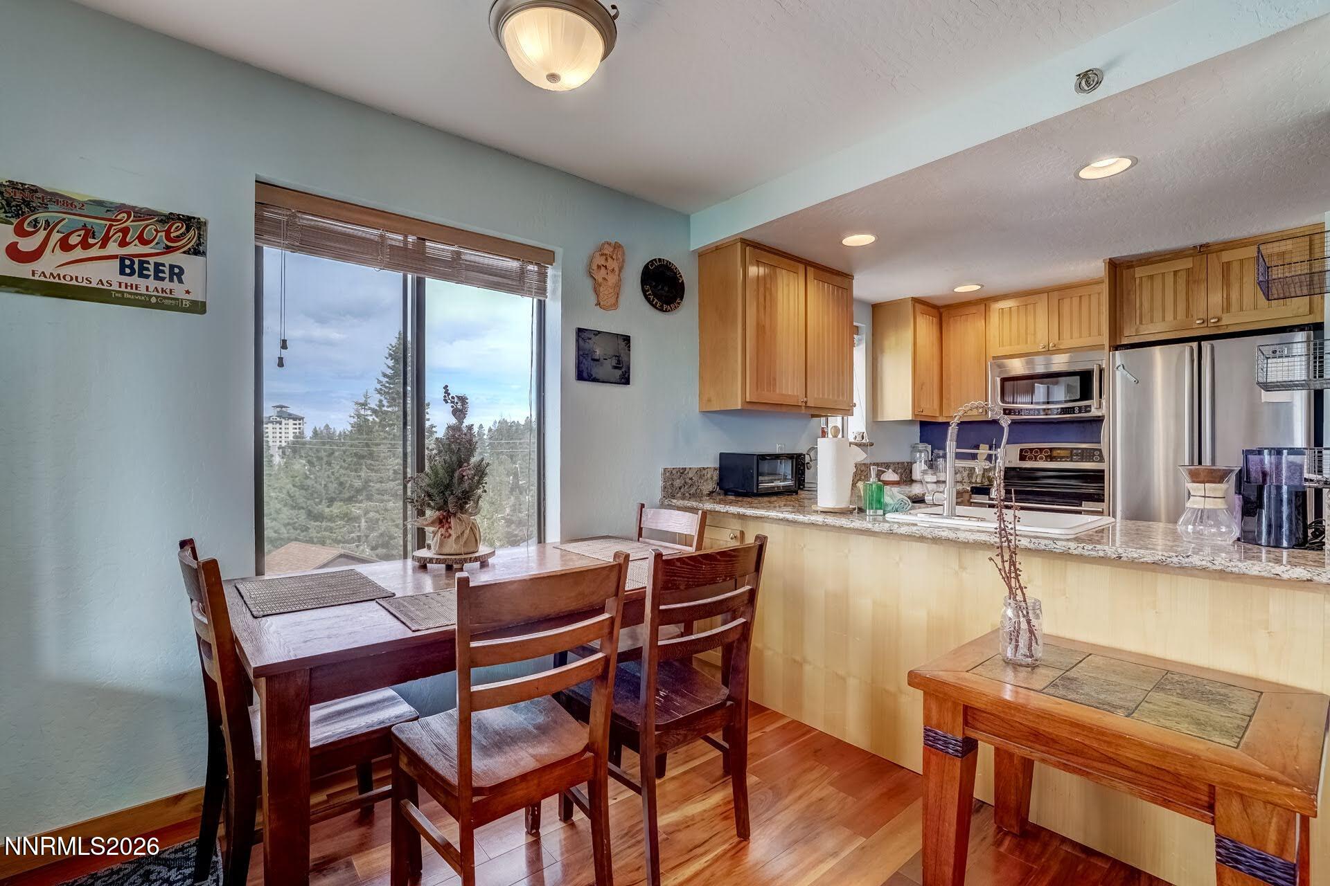 495 Tramway Drive, Unit 7 Stateline, NV 89449 - Photo 9 of 31 a dining room with stainless steel appliances granite countertop a table chairs and a wooden floor