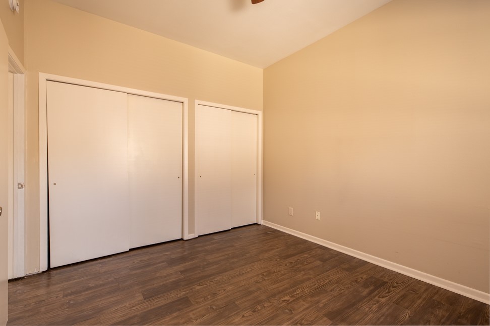 712 Graham Place, Unit 305 Austin, TX 78705 - Photo 15 of 18 Unfurnished bedroom featuring multiple closets and dark wood-type flooring