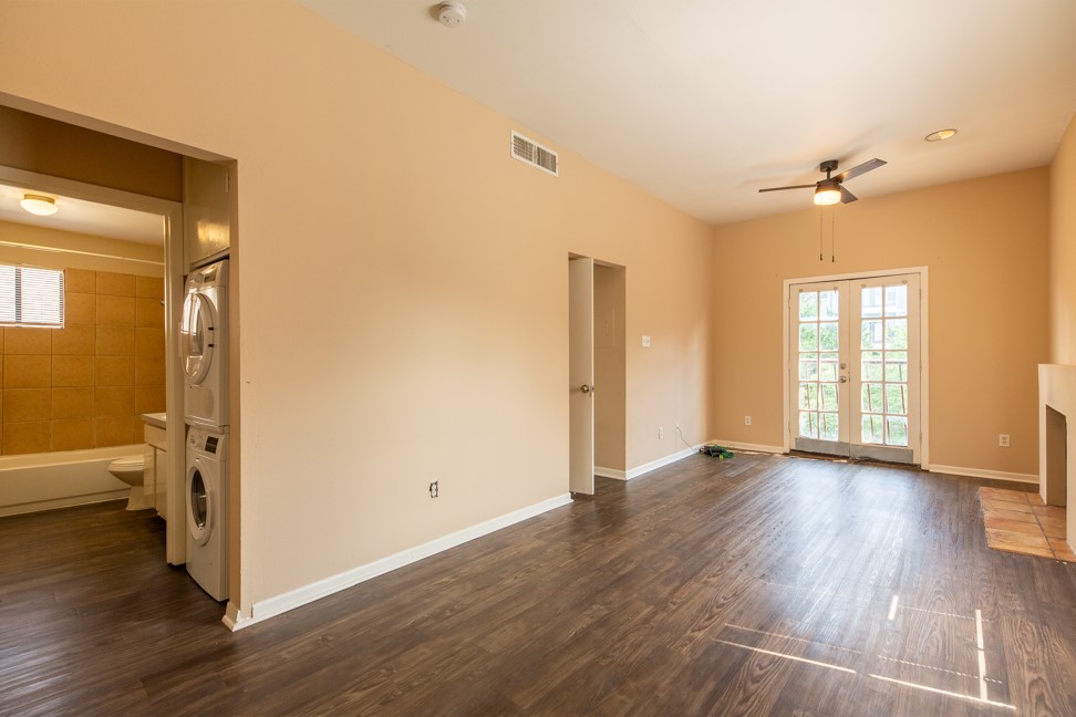 712 Graham Place, Unit 305 Austin, TX 78705 - Photo 3 of 18 Unfurnished living room with stacked washing machine and dryer, dark wood-style flooring, ceiling fan, and french doors