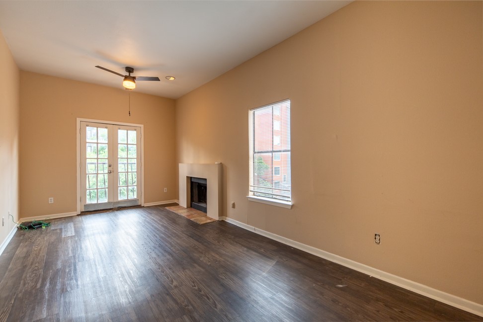 712 Graham Place, Unit 305 Austin, TX 78705 - Photo 4 of 18 Unfurnished living room featuring a fireplace with flush hearth, dark wood-style floors, french doors, and a ceiling fan