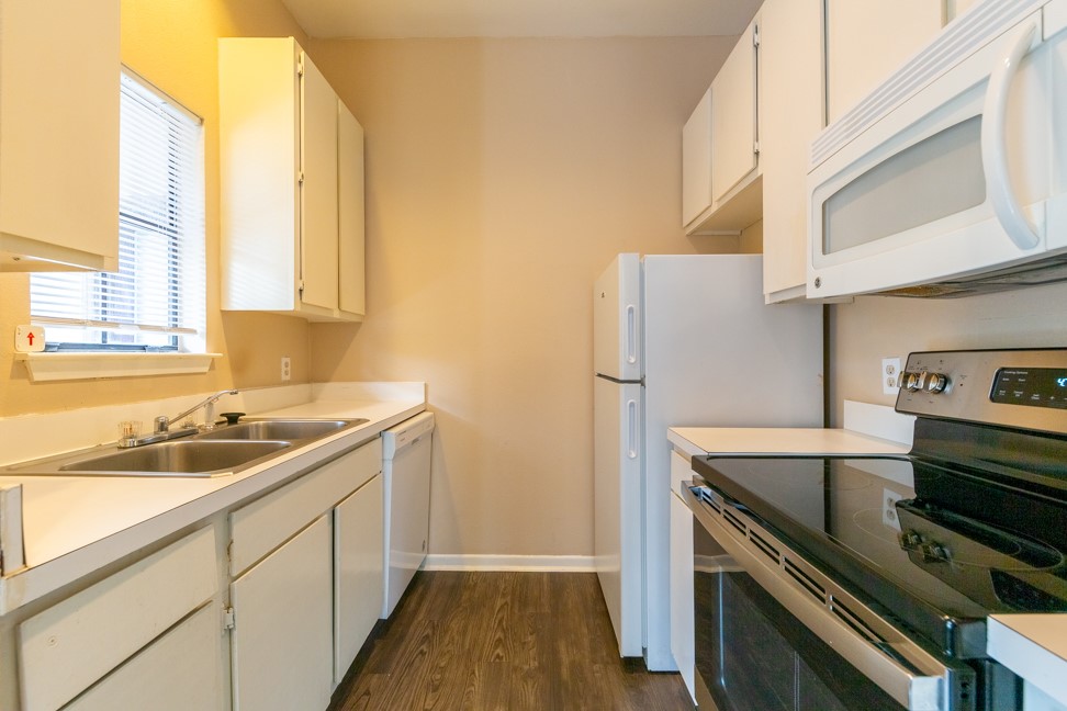 712 Graham Place, Unit 305 Austin, TX 78705 - Photo 7 of 18 Kitchen featuring white appliances, dark wood finished floors, light countertops, and white cabinetry