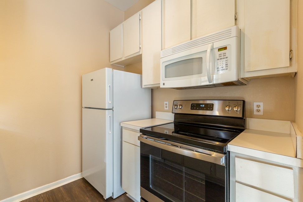 712 Graham Place, Unit 305 Austin, TX 78705 - Photo 8 of 18 Kitchen with white appliances, light countertops, dark wood finished floors, and white cabinets